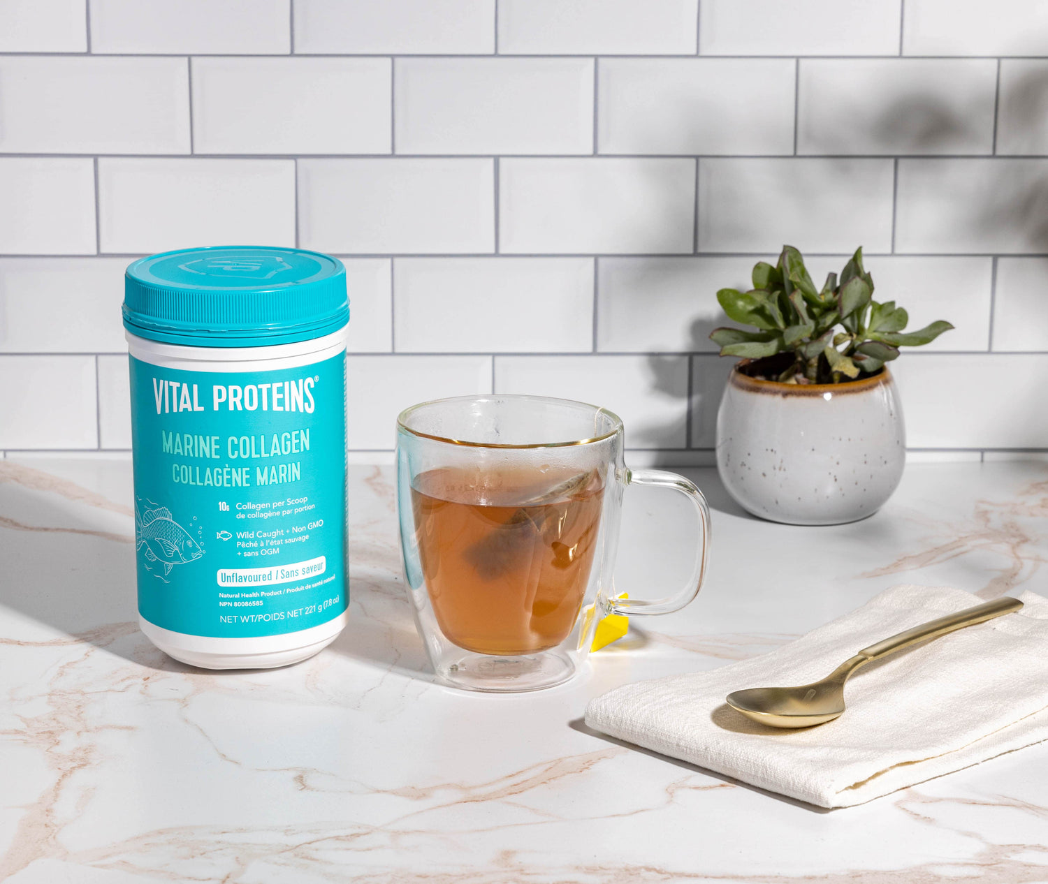 Marine Collagen container on a kitchen counter with a glass of tea.